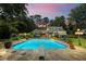 Backyard pool is surrounded by manicured lawn with lush trees, patio space, and screened-in porch at 555 Valley Hall Dr, Atlanta, GA 30350