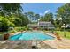 Backyard pool is surrounded by manicured lawn with lush trees, patio space, and screened-in porch at 555 Valley Hall Dr, Atlanta, GA 30350