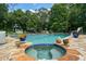 Gorgeous in-ground pool with attached hot tub and surrounding stone patio complemented by lush landscaping at 555 Valley Hall Dr, Atlanta, GA 30350