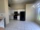 Kitchen featuring white cabinets, black appliances, and tile flooring at 76 Daisy Meadow Trl, Lawrenceville, GA 30044