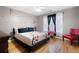 Stylish bedroom with hardwood floors, red accents, floral-patterned bedding, and ample natural light at 1227 Castle Point Sw Ct, Conyers, GA 30094