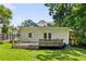 Exterior of the home's back with a green lawn, access doors, and small wooden deck, all surrounded by trees at 240 Melrose Ave, Decatur, GA 30030