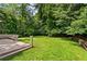 Spacious backyard featuring a lush green lawn, bordered by mature trees, and wooden deck attached to the house at 240 Melrose Ave, Decatur, GA 30030