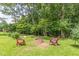 A backyard fire pit sits between two chairs in a lush green yard with surrounding trees at 7234 Post Rd, Winston, GA 30187