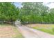 View of gated driveway flanked by mature trees and shrubs for privacy at 7234 Post Rd, Winston, GA 30187