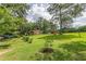 Wide backyard view with screened porch, pool, and spacious green lawn with trees at 7234 Post Rd, Winston, GA 30187