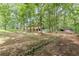 A home with carport sits on a wide, grassy lot, accented with mature trees and natural rock borders at 7234 Post Rd, Winston, GA 30187