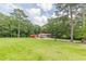 Large front yard featuring mature trees, long driveway, and a home with a red roof at 7234 Post Rd, Winston, GA 30187