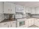 Clean kitchen with white cabinets, appliances, mosaic backsplash, and a double basin sink at 7234 Post Rd, Winston, GA 30187