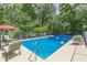 Sparkling in-ground pool with lounge chairs and seating surrounded by lush trees at 7234 Post Rd, Winston, GA 30187