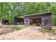 Large shed with open doors offers ample storage space for tools and equipment in a wooded backyard setting at 7234 Post Rd, Winston, GA 30187
