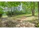 A peaceful, grassy lot showcases natural landscaping bordered by a stone wall and privacy hedging at 7234 Post Rd, Winston, GA 30187