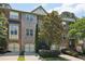Three-story brick townhomes with garages, manicured landscaping, and mature trees offer curb appeal at 1986 Cobblestone Ne Cir, Atlanta, GA 30319