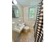 Compact full bathroom with white fixtures, patterned floor and a window at 3975 N Sharon Church N Rd, Loganville, GA 30052
