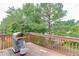 View of a wood deck with a gas grill, wood railing and view of green trees at 571 Oak Vista Ct, Lawrenceville, GA 30044