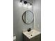 Modern bathroom with a circular mirror, stylish light fixture, and sleek vanity at 6906 Shangrila Way, Riverdale, GA 30296