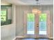 Bright dining area featuring a stylish light fixture and patio doors leading to an outdoor deck and green scenery at 6906 Shangrila Way, Riverdale, GA 30296