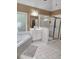 Bathroom featuring a bathtub, shower with gold trim, a vanity, a mirror, and a small window at 3930 Regal Oaks Dr, Suwanee, GA 30024