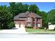 Charming two-story red brick home with arched windows, attached garage and manicured front lawn, surrounded by mature trees at 3930 Regal Oaks Dr, Suwanee, GA 30024