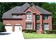 Charming two-story red brick home with arched windows, shutters, attached garage and manicured front lawn at 3930 Regal Oaks Dr, Suwanee, GA 30024