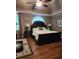 This bedroom boasts a dark-wood bed frame, ceiling fan, bedside lamps and window at 3930 Regal Oaks Dr, Suwanee, GA 30024