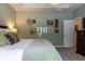 Relaxing main bedroom with light green walls, decorative wall hangings, and a dark wood dresser at 2099 Lakeview Bend Way, Buford, GA 30519