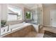 This bathroom features a garden tub, glass-enclosed shower, neutral tile and backyard view at 3755 Valleyway Rd, Cumming, GA 30040