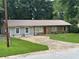 Charming single-story home featuring a metal roof, brick accents, and a spacious front yard with an extended driveway at 499 Oak Way, Lawrenceville, GA 30046