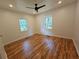 A bright bedroom features hardwood floors, a ceiling fan, and natural light from two windows at 1497 Elizabeth Ln, East Point, GA 30344