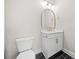 Stylish powder room with black tile floor, white vanity with gold fixtures, toilet, and large mirror at 419 Crestmont Ln, Canton, GA 30114