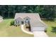 An aerial front elevation of the home with a lush and mature tree line and manicured lawn at 555 Flintlock Dr, Dacula, GA 30019