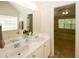 Well-lit bathroom with double sinks, a large mirror, and a view into the bedroom at 555 Flintlock Dr, Dacula, GA 30019