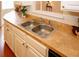 This kitchen sink area has warm countertops and cabinets and looks into the living room at 555 Flintlock Dr, Dacula, GA 30019