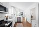 Bright kitchen features white cabinets, stainless steel appliances, and hardwood floors with view to a dining area at 138 Woodlawn Ave, Decatur, GA 30030
