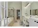 Bright bathroom featuring double sinks, vanity and separate tub and shower at 4825 Whispering Pine Way, Cumming, GA 30028