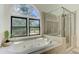 Bathroom featuring a soaking tub beneath a large window and a glass shower at 4825 Whispering Pine Way, Cumming, GA 30028
