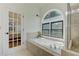 Bright bathroom featuring a soaking tub beneath an arched window at 4825 Whispering Pine Way, Cumming, GA 30028