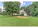 Expansive front yard with mature trees, garden beds, and lush lawn offering privacy at 4825 Whispering Pine Way, Cumming, GA 30028