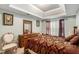 Bedroom featuring a tray ceiling, a wooden dresser, and a comfortable seating area at 11961 Markham Way, Hampton, GA 30228