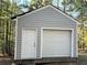 A large storage shed with a garage door and entry door sits on the wooded property at 188 A Macedonia Rd, White, GA 30184