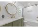 Bright bathroom featuring round mirror, green cabinet, white countertop and tub at 3155 Zion St, Scottdale, GA 30079