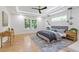 Spacious main bedroom featuring hardwood floors, ceiling fan, modern lighting, and many windows at 3155 Zion St, Scottdale, GA 30079