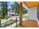 Close-up of the porch with natural wood posts and ceiling, metal railings, and lush landscaping at 3155 Zion St, Scottdale, GA 30079