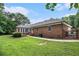 Spacious backyard with lush green lawn, mature trees, and a brick exterior, creating a serene and private outdoor space at 3003 Hanover Se Ln, Conyers, GA 30094