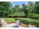 Lush backyard featuring a well-maintained lawn, mature trees, landscaping, and a brick-lined patio area with a fire pit at 3003 Hanover Se Ln, Conyers, GA 30094