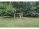 Backyard with a swing set, slide, and a play area, all surrounded by lush green grass and mature trees, perfect for recreation at 3003 Hanover Se Ln, Conyers, GA 30094