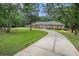 Wide shot of the home's exterior, long driveway, and manicured lawn surrounded by mature trees at 3003 Hanover Se Ln, Conyers, GA 30094