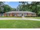 Charming single-story brick home with a green lawn, large driveway, and lush, mature trees at 3003 Hanover Se Ln, Conyers, GA 30094