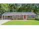 Charming brick home features a covered carport, red front door and lush landscaping at 365 Norcross St, Roswell, GA 30075