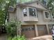 Three-car garage with tan doors, multiple windows and stone accents at 390 Hunt River Way, Suwanee, GA 30024